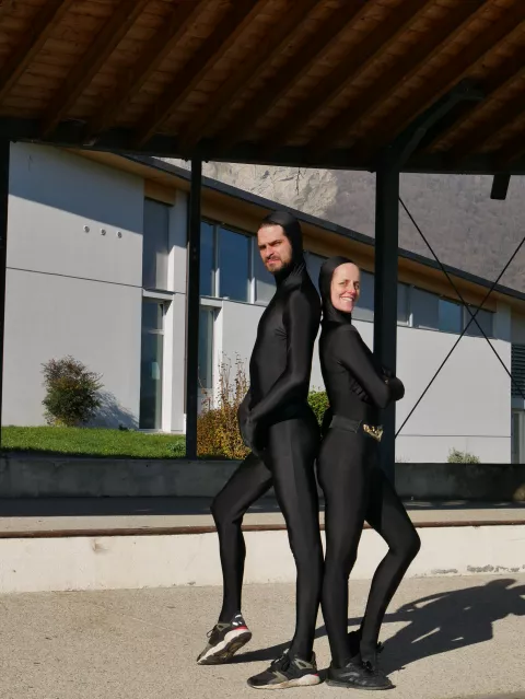 Un homme et une femme en combinaison noire dos à dos © Ville de Crolles