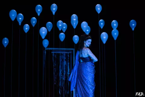 Ue femme habillée en bleu sur fond noir parsemé de ballons bleus © Fanny Desbaumes / FAD