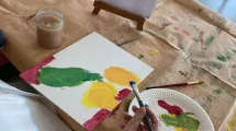 Atelier dans une USLD (unités de soins de longue durée) © CHUGA zoom sur les mains d'une personne agée peignant sur une feuille posée sur une tablE © CHUGA