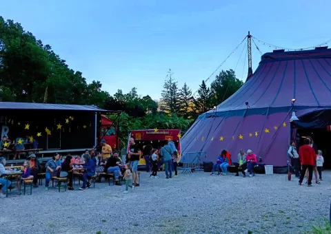 spectateurs rassemblés devant une tente violette et attablés devant un bar